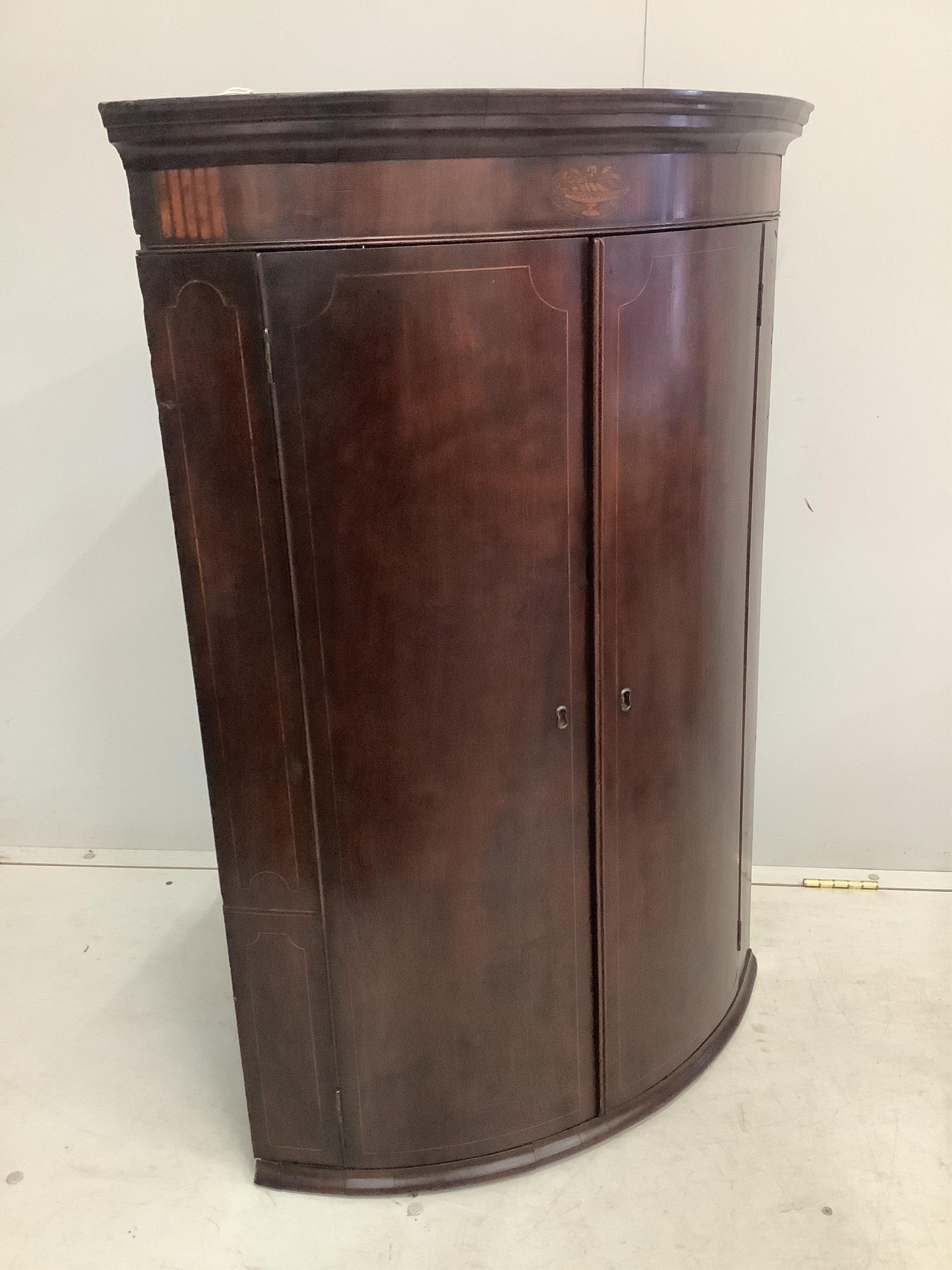 A George III inlaid mahogany bow front hanging corner cupboard, width 74cm, depth 50cm, height 107cm
